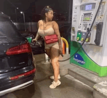 a woman is standing next to a car at a gas station pumping gas .