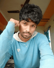 a young man wearing a blue sweatshirt with the letter t on it