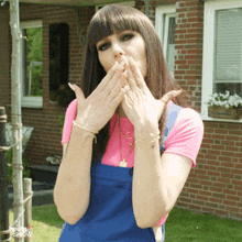 a woman covering her mouth with her hands in front of a brick building with the words heute show on the bottom