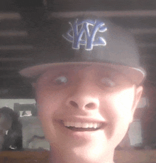 a young man wearing a nys hat smiles for the camera