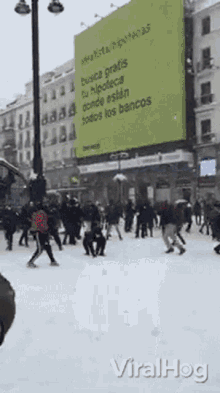 a crowd of people are walking in the snow in front of a large billboard that says busca gratis tu hipoteca donde estan todos los bancos