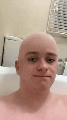 a man with a shaved head is taking a bath