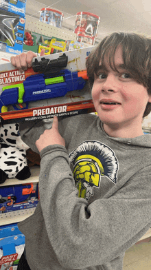 a boy in a predator shirt points to a toy