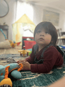 a baby is laying on his stomach on the floor playing with toys