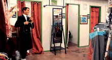 a man in a suit is standing in a dressing room with a sign on the wall that says " no smoking "