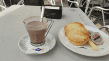 a cup of hot chocolate next to a plate of bread