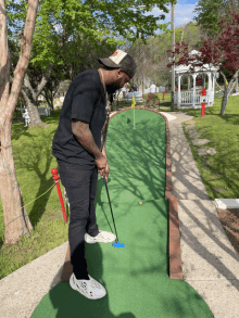 a man in a black shirt is playing a game of mini golf