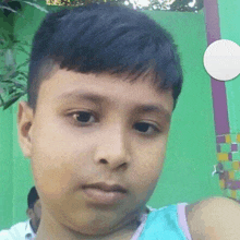 a young boy is taking a selfie in front of a green wall with a faucet in the background .