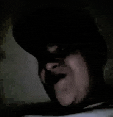 a close up of a person 's face in a dark room with a hat on .