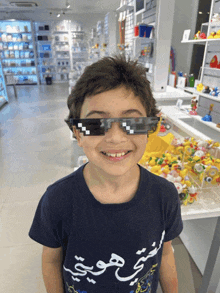 a young boy wearing sunglasses and a shirt with arabic writing on it smiles at the camera