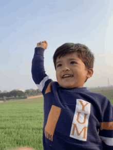 a young boy wearing a blue sweater that says yum on it