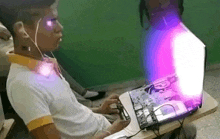 a man is sitting in front of a laptop with a purple light coming out of it