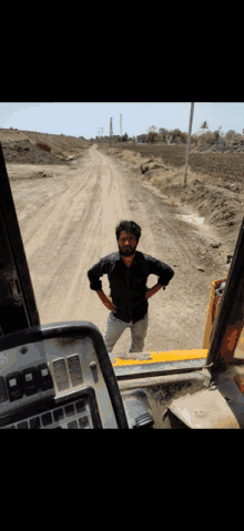 a man is standing on a dirt road in front of a tractor