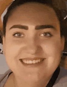 a close up of a woman 's face smiling with a bandana on her head .