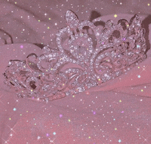 a pink tiara is sitting on top of a pink cloth on a pink background .