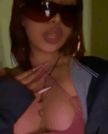 a woman wearing sunglasses and a pink top has a necklace with the letter a on it