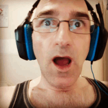 a man wearing glasses and blue headphones makes a surprised face