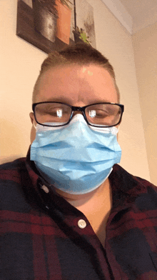 a man wearing glasses and a face mask looks at the camera