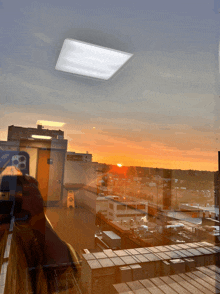 a sunset is reflected in a window with a sign that says ' caution wet floor '