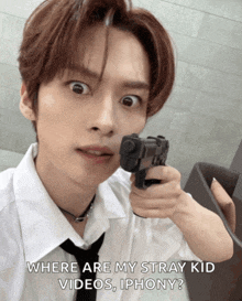 a young man in a white shirt and tie is pointing a gun at the camera with the caption where are my stray kid videos iphoney