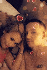 a man and a woman laying on a bed with hearts floating around them