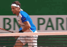 a tennis player in front of an ad for bn pari