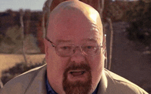 a bald man with glasses and a beard is making a face