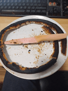 a burnt pizza on a white plate with a knife