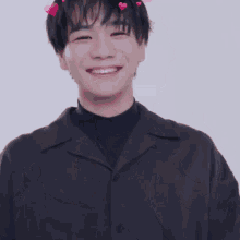 a young man wearing a black shirt with hearts on his head smiles