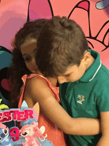 a boy and girl are hugging in front of a lilo and stitch birthday cake