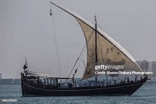 a large sailboat with a large sail is floating on top of a body of water .