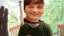 a young boy wearing a green shirt is smiling and looking at the camera .