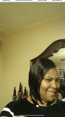 a woman is smiling in front of a mirror while wearing a black and white striped shirt