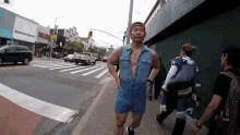 a man in a denim jumpsuit is running on a sidewalk in front of a building that says american apparel