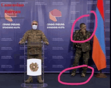 a man wearing a mask stands at a podium with caucasus bureau telegram written on the wall behind him