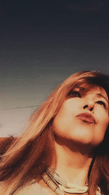 a woman with long hair and a nose ring looks up into the sky