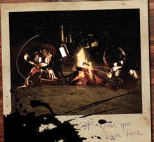 a picture of two robots sitting around a campfire with the words wish you were here