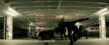 a man is doing a handstand in a parking garage while a police car is parked in the background .