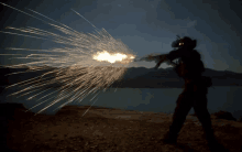 a man is holding a gun with sparks coming out of it at night