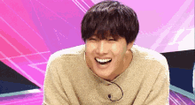 a young man wearing a sweater is laughing with his mouth open