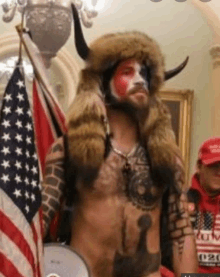 a shirtless man in a native american costume is standing in front of an american flag