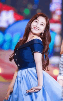 a woman in a blue off the shoulder dress is smiling