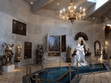 a museum with a chandelier hanging from the ceiling and a pool of water in the middle of the room .