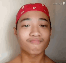 a shirtless young man wearing a red bandana on his head .