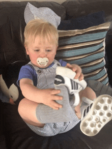 a baby with a pacifier in his mouth is sitting on a couch