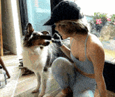 a woman kneeling down next to a dog wearing a hat