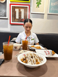 a woman sits at a table with a plate of food and a cup of iced tea