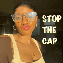 a woman wearing glasses stands in front of a sign that reads stop the cap