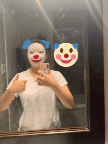 a woman taking a picture of herself in a mirror with a clown face on her face