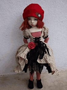 a doll wearing a red hat and a dress with a rose around her waist